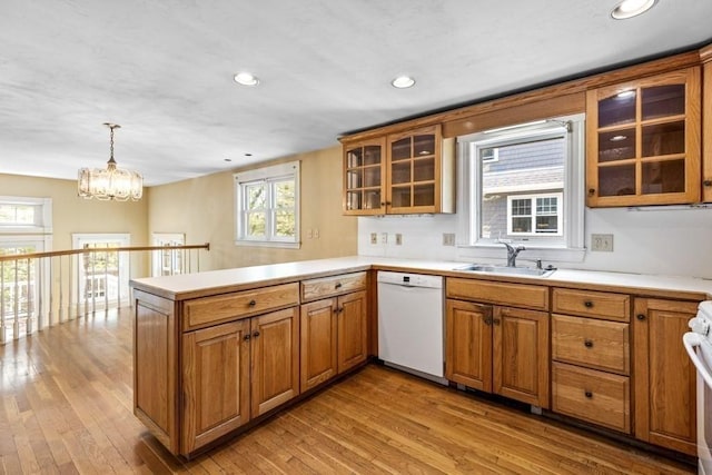 kitchen with a sink, a peninsula, dishwasher, and brown cabinets