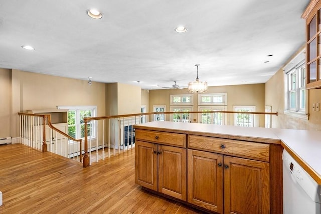 kitchen featuring brown cabinetry, dishwasher, light countertops, a peninsula, and light wood-style floors