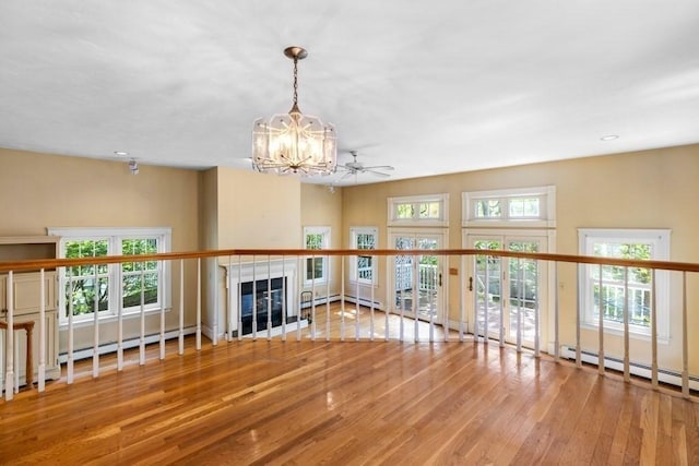 unfurnished living room with an inviting chandelier, wood-type flooring, recessed lighting, a baseboard heating unit, and a tiled fireplace