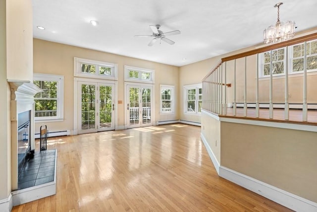 unfurnished living room featuring a glass covered fireplace, baseboards, a baseboard radiator, and ceiling fan with notable chandelier