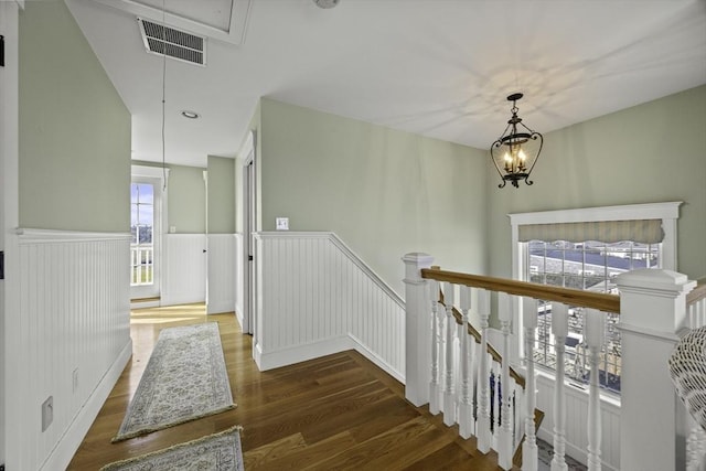 stairs with wood-type flooring and an inviting chandelier