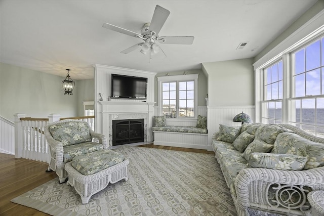 living room featuring hardwood / wood-style floors, ceiling fan with notable chandelier, and a premium fireplace