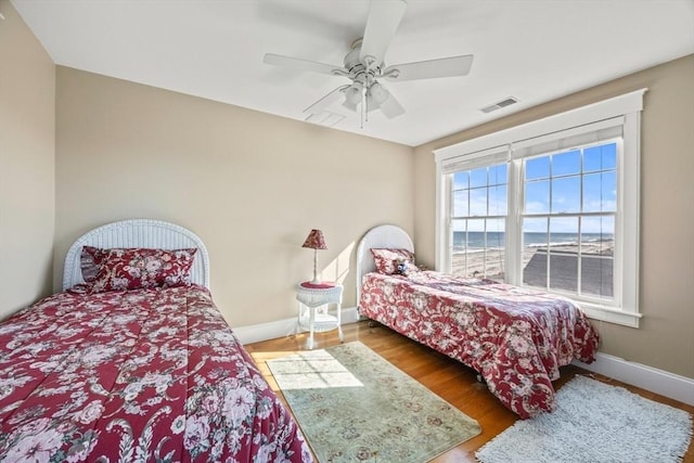 bedroom featuring hardwood / wood-style floors, ceiling fan, and a water view