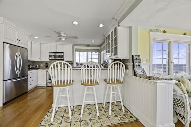 kitchen with kitchen peninsula, appliances with stainless steel finishes, and white cabinetry