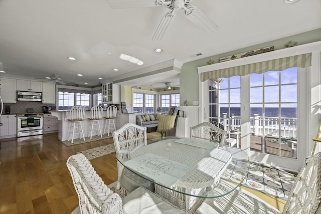 dining space featuring ceiling fan, dark hardwood / wood-style flooring, and a water view