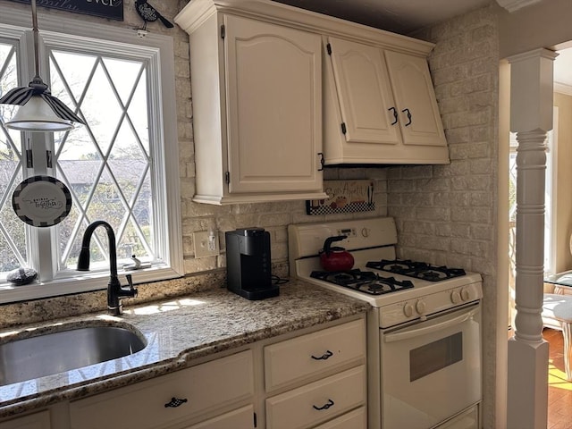 kitchen with white cabinets, a sink, white gas range, and a healthy amount of sunlight