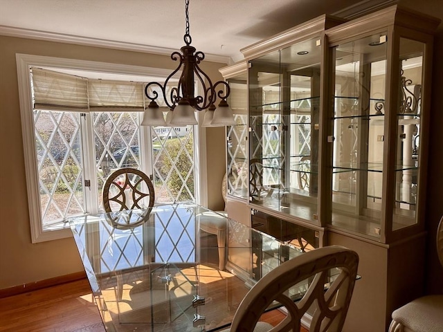 dining area with wood finished floors, baseboards, a chandelier, and crown molding