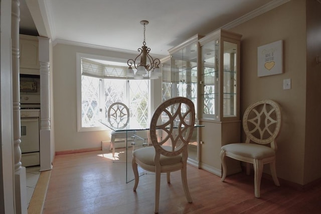 dining area featuring light wood-style flooring, baseboards, a notable chandelier, and ornamental molding