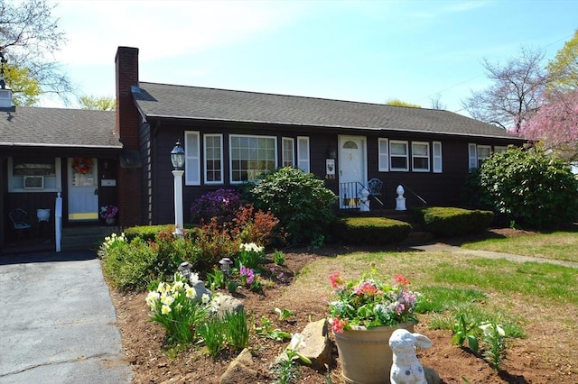 single story home with driveway, a shingled roof, and a chimney
