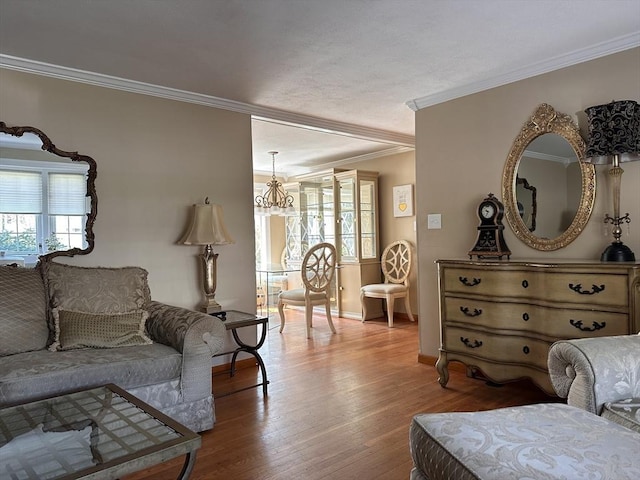 living room featuring baseboards, wood finished floors, an inviting chandelier, and ornamental molding