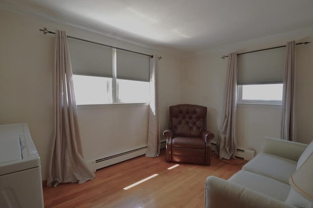 living area featuring a baseboard radiator, washer / dryer, crown molding, and light wood-style flooring