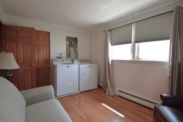 clothes washing area featuring baseboard heating, crown molding, laundry area, and light wood-style flooring