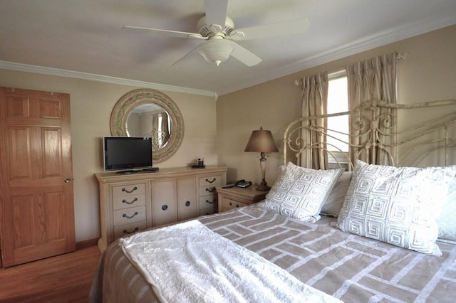 bedroom featuring ceiling fan, baseboards, crown molding, and wood finished floors