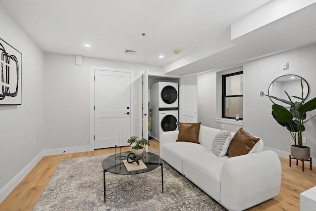 living room featuring stacked washer / dryer and hardwood / wood-style flooring