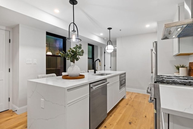 kitchen featuring a kitchen island with sink, exhaust hood, white cabinets, decorative light fixtures, and stainless steel appliances