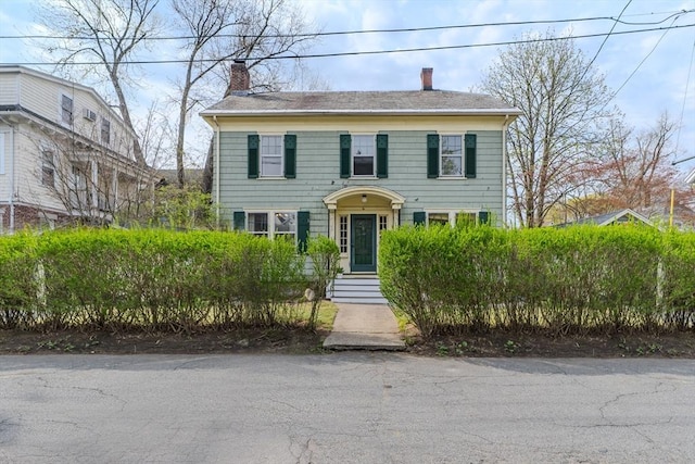 colonial house with a chimney and a shingled roof
