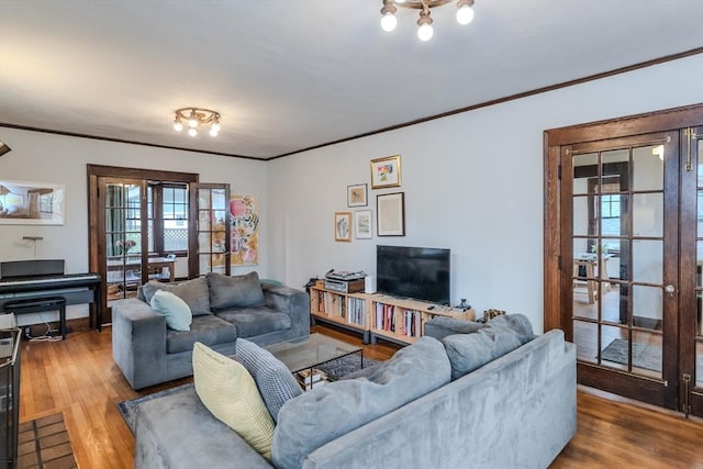 living room with wood finished floors, french doors, crown molding, and baseboards