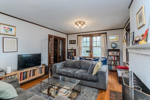 living room with a fireplace, wood finished floors, and crown molding
