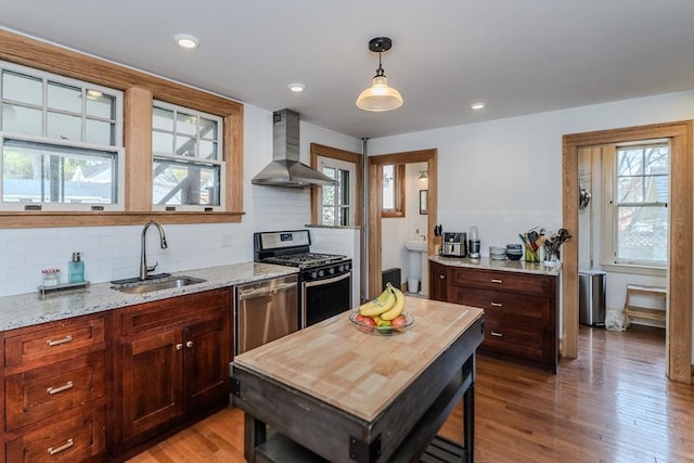 kitchen featuring wall chimney exhaust hood, a sink, appliances with stainless steel finishes, and plenty of natural light