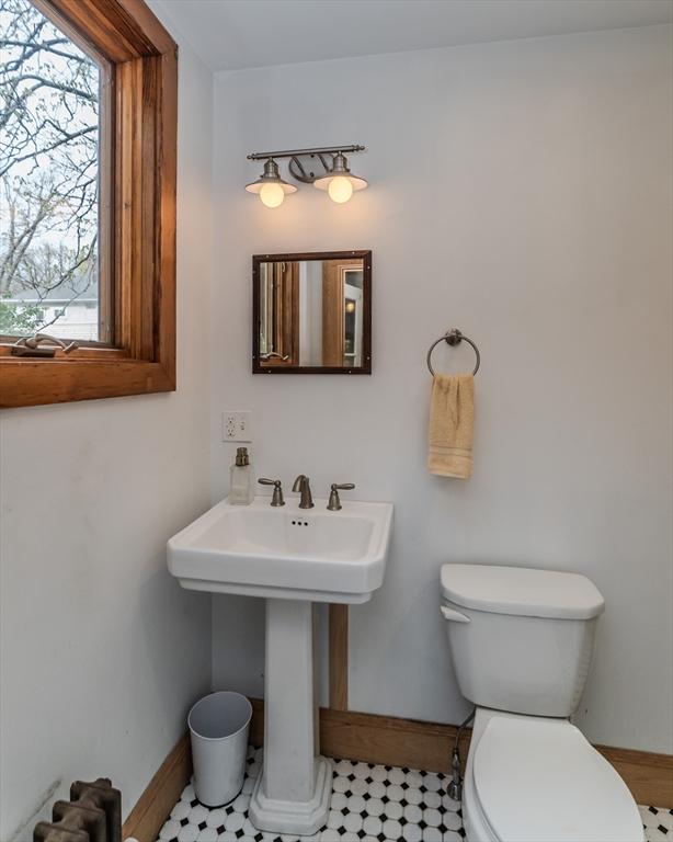 bathroom with toilet, a wealth of natural light, and baseboards