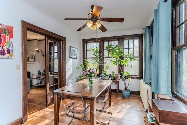 office area featuring light wood-style floors, a ceiling fan, crown molding, and baseboards