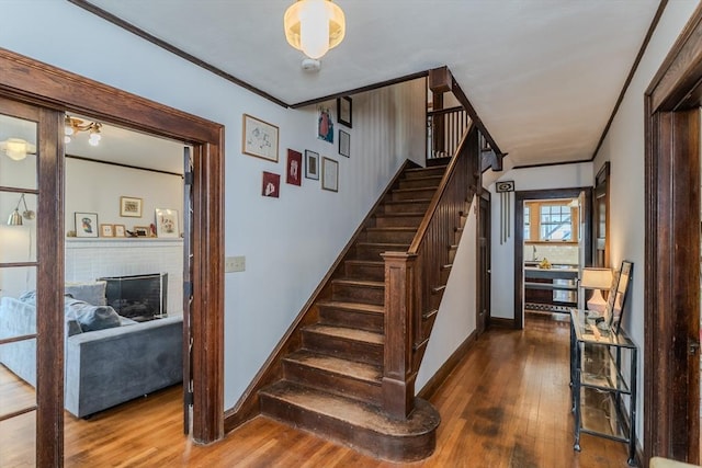 staircase with baseboards, hardwood / wood-style flooring, a fireplace, and crown molding