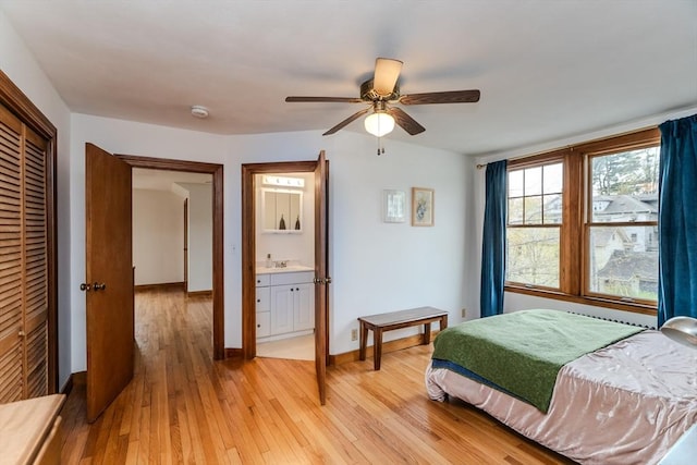 bedroom featuring light wood-style flooring, a closet, a sink, baseboards, and a ceiling fan