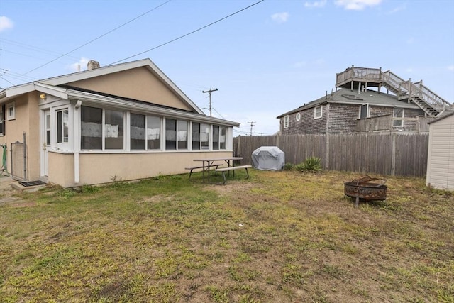 exterior space with a sunroom, an outdoor fire pit, and fence