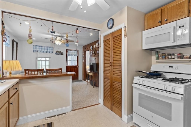 kitchen featuring visible vents, baseboards, ceiling fan, brown cabinets, and white appliances