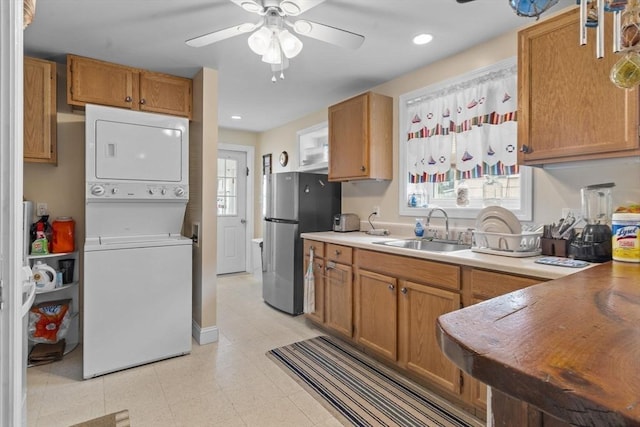 kitchen with stacked washer / dryer, plenty of natural light, freestanding refrigerator, and a sink