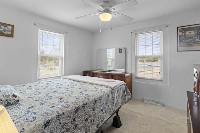 carpeted bedroom featuring visible vents, multiple windows, and a ceiling fan