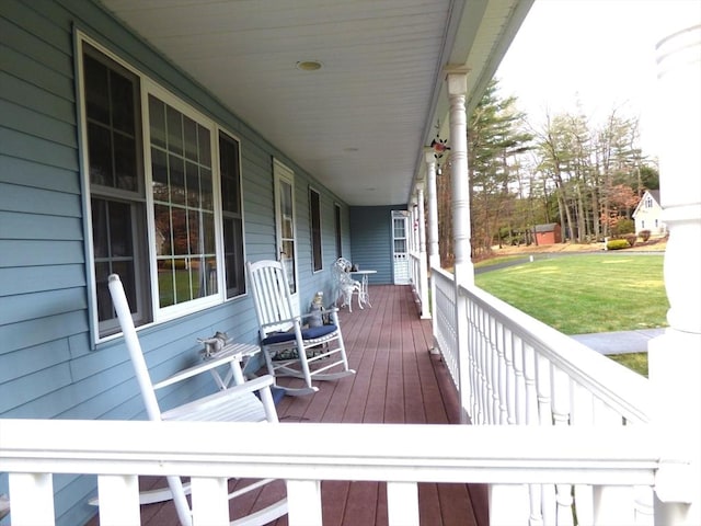 wooden deck with covered porch and a lawn