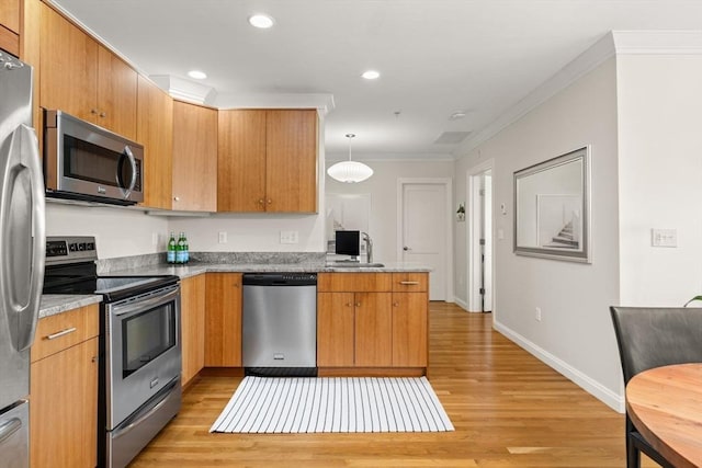 kitchen featuring stainless steel appliances, light wood finished floors, a sink, crown molding, and baseboards