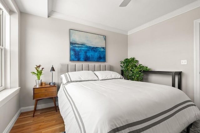 bedroom with wood finished floors, ornamental molding, baseboards, and ceiling fan