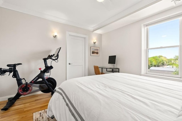 bedroom with wood finished floors, multiple windows, crown molding, and baseboards