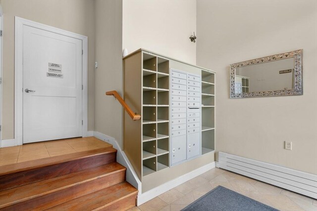 stairs with tile patterned floors, baseboards, and baseboard heating