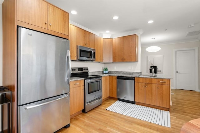 kitchen with stainless steel appliances, crown molding, a sink, light wood-style floors, and a peninsula