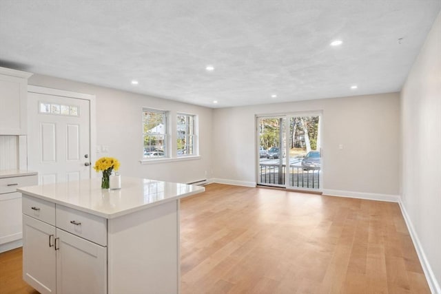 kitchen with baseboards, light countertops, light wood-type flooring, white cabinetry, and recessed lighting