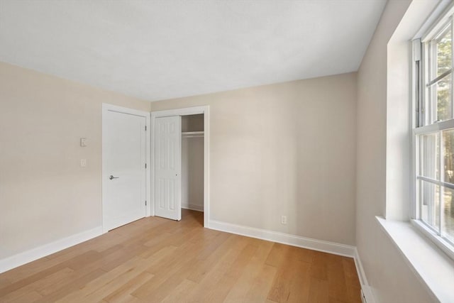 unfurnished bedroom featuring light wood-style floors, a closet, and baseboards