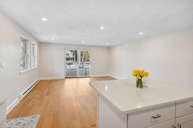 kitchen with light wood finished floors, recessed lighting, light countertops, a baseboard heating unit, and baseboards