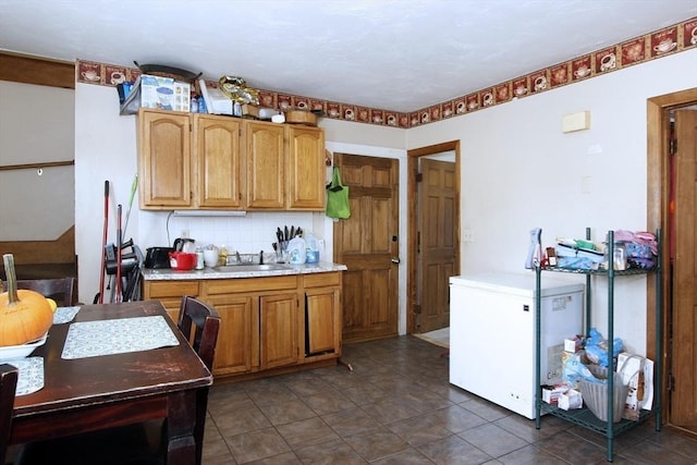 kitchen featuring refrigerator, backsplash, dark tile patterned flooring, and sink