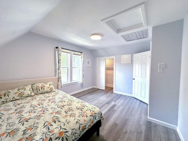 121 N Main St, Natick, MA 01760 - bedroom featuring attic access, wood finished floors, vaulted ceiling, a closet, and a walk in closet
