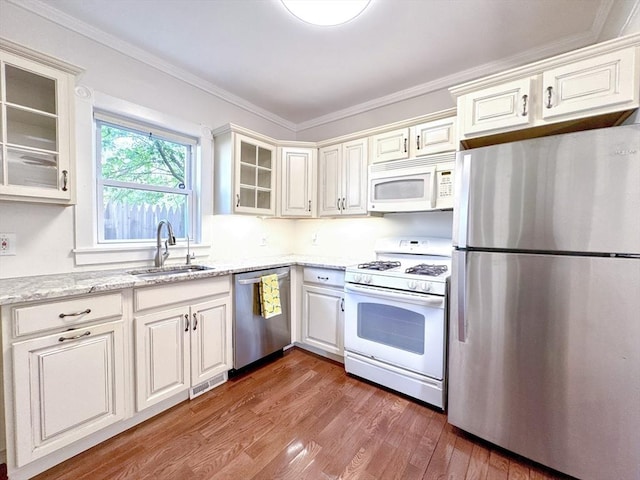 121 N Main St, Natick, MA 01760 - kitchen with stainless steel appliances, wood finished floors, light stone counters, glass insert cabinets, and crown molding