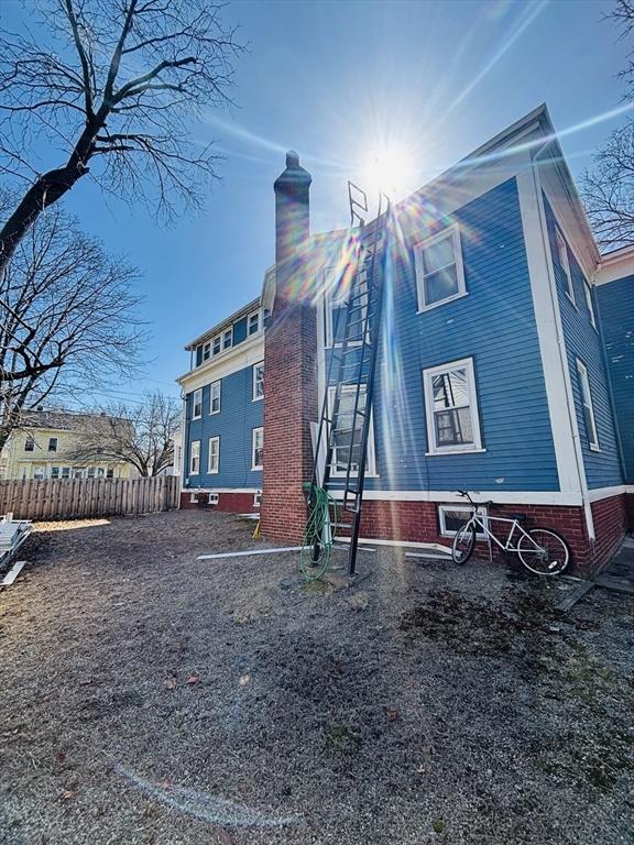 view of side of property featuring fence and a chimney
