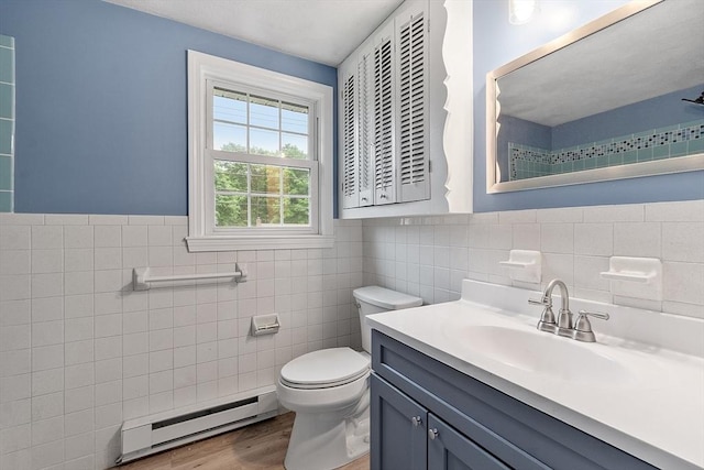 66 Park St, Pepperell, MA 01463 - full bathroom featuring baseboard heating, tile walls, wood finished floors, vanity, and wainscoting
