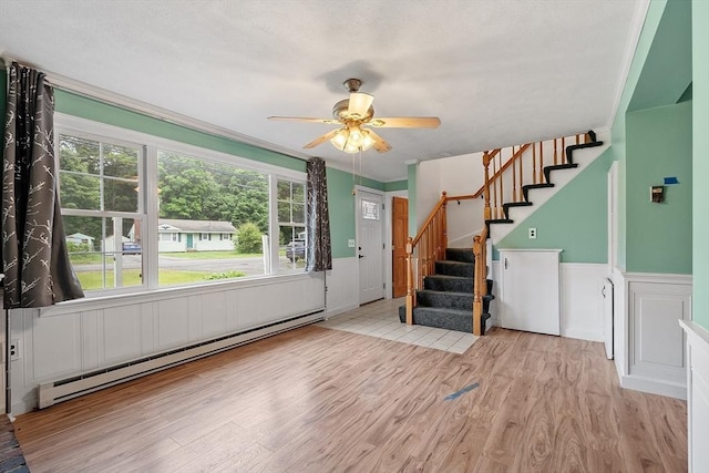 66 Park St, Pepperell, MA 01463 - entrance foyer featuring a baseboard heating unit, wainscoting, wood finished floors, a ceiling fan, and stairway