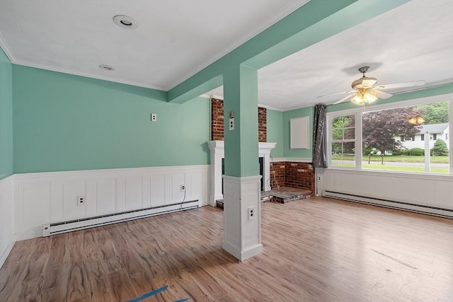 66 Park St, Pepperell, MA 01463 - empty room with baseboard heating, wood finished floors, a wainscoted wall, ceiling fan, and a fireplace
