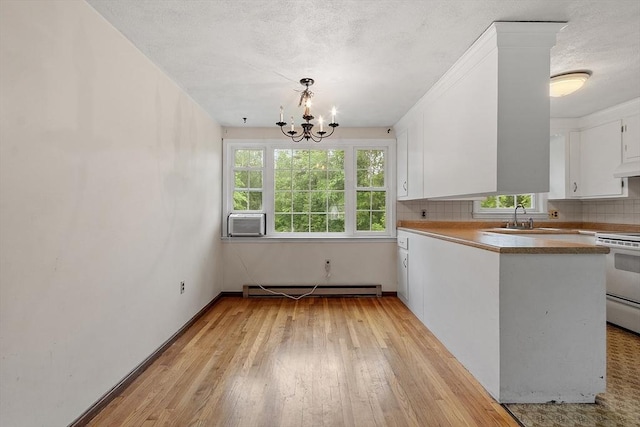 66 Park St, Pepperell, MA 01463 - kitchen featuring a baseboard radiator, white range with electric cooktop, white cabinets, light wood-style floors, and a chandelier