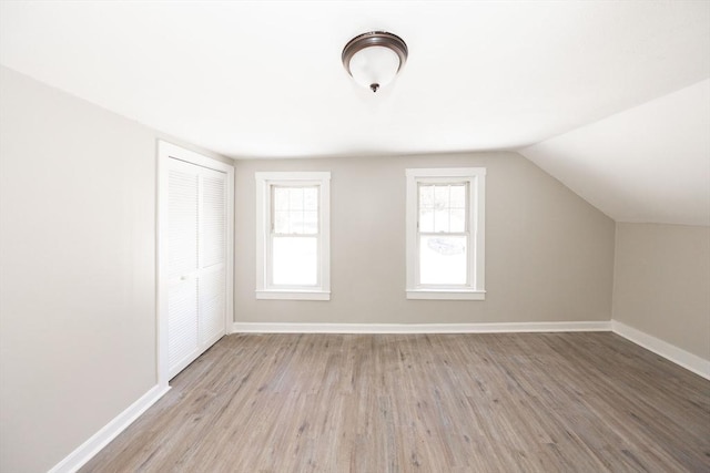 additional living space with light wood-style flooring, baseboards, and vaulted ceiling