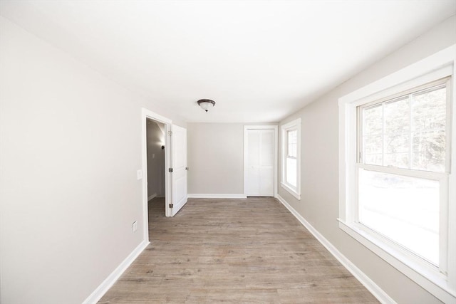 unfurnished room with baseboards and light wood-style floors